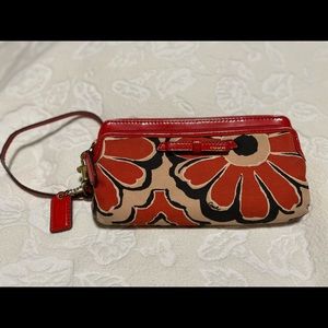 Coach brand orange/cream floral wristlet wallet.